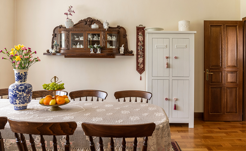 Wooden chairs at table with flowers in bright elegant dining room interior with door