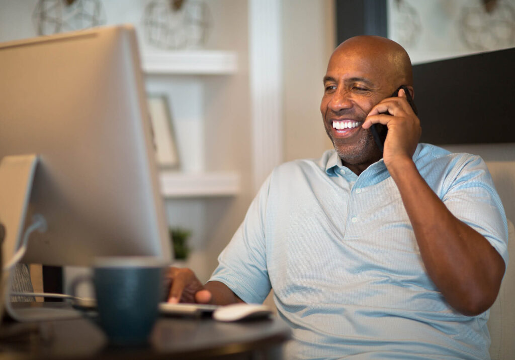 man talking on the phone and looking at a computer screen